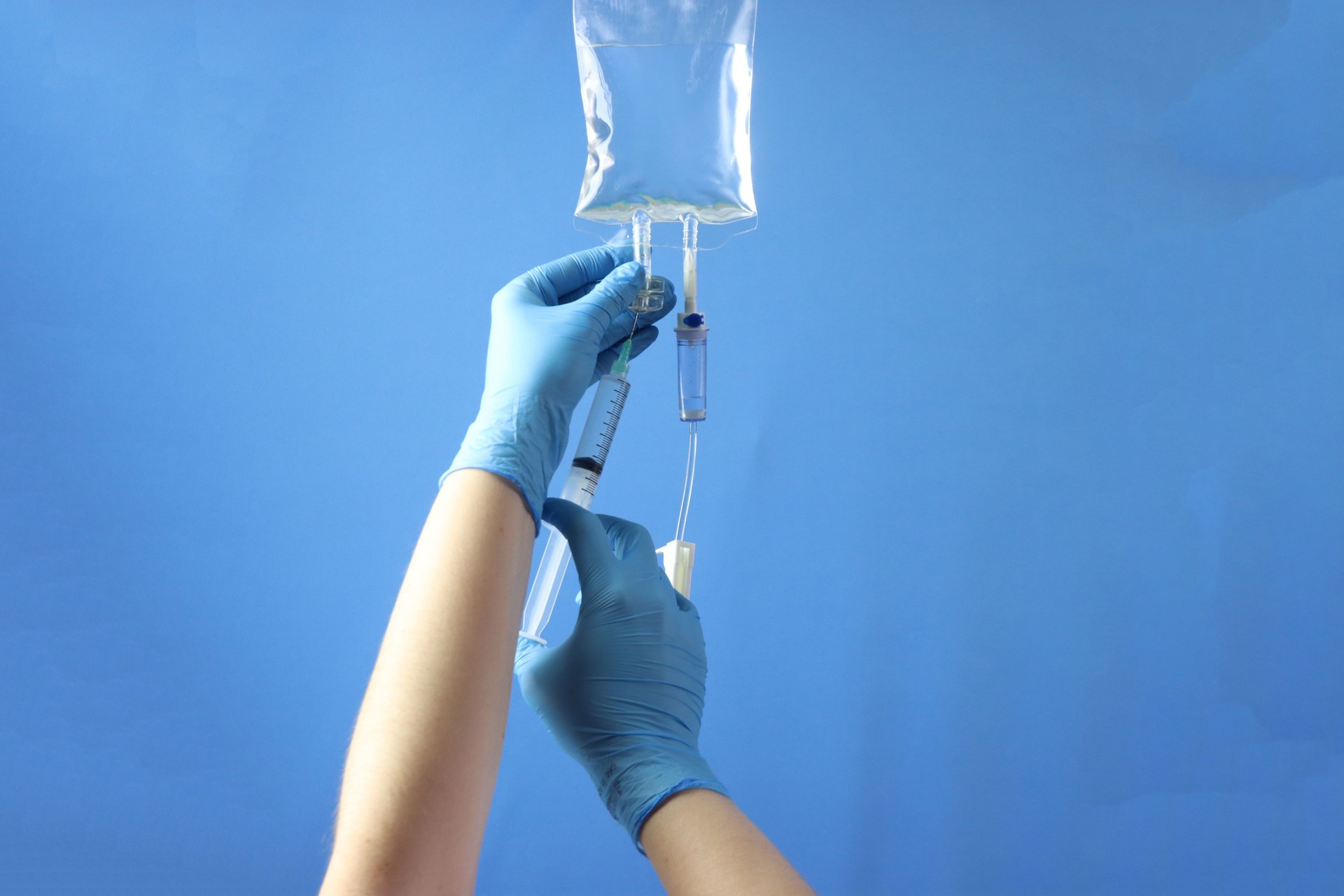 Drug bag with a infusion set connected to delivery the drug to the pacient. Professional holding the bag to infuse the drug with a syringe